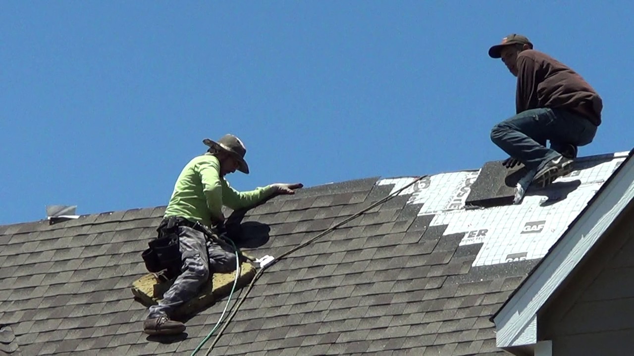 Two roofers working on the roof of a house.