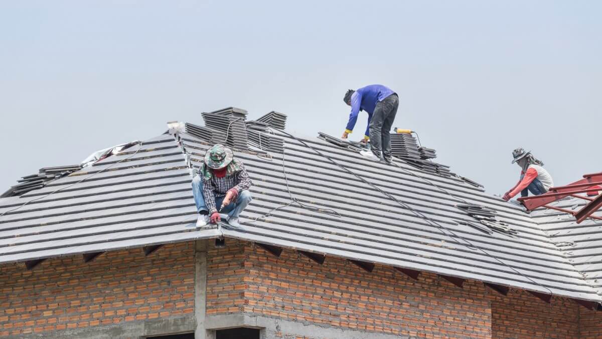 a couple of men working on a roof.