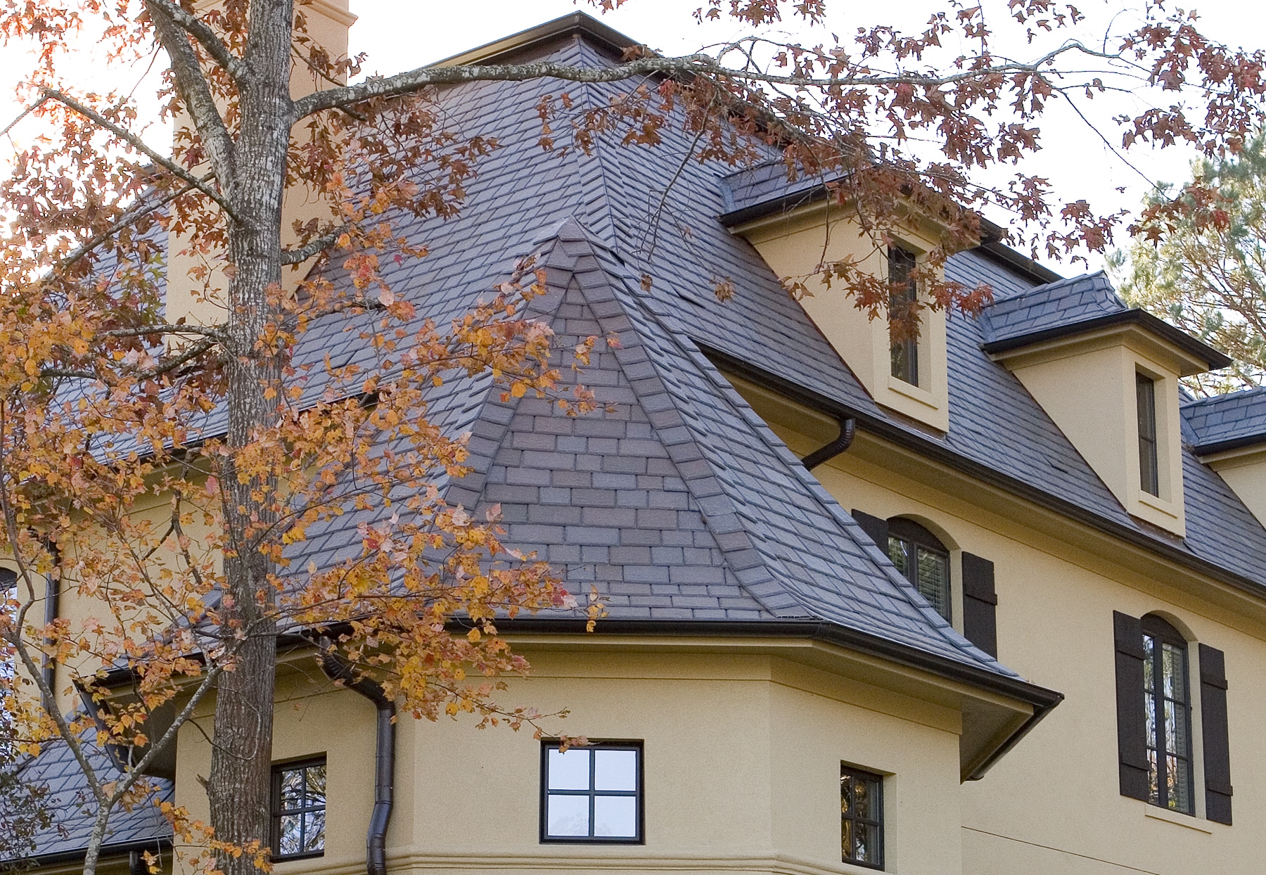 A house in the fall with a tan roof that may require roof replacement.